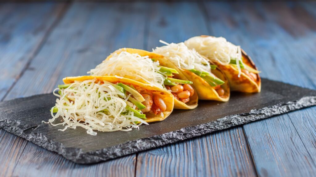 Mexican tacos with meat, beans, avocado, cheese and tomato sauce