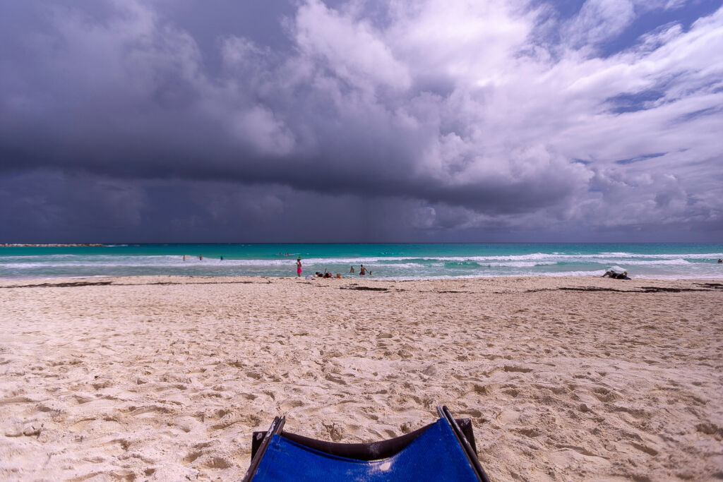 Cancun, Mexico / October 2, 2015: Surfers at Cancun beach. Cancun Mexico beautiful caribbean sea on a sunny day and cloudy sky. Exotic Paradise. Travel, Tourism and Vacations Concept. Tropical Resort.