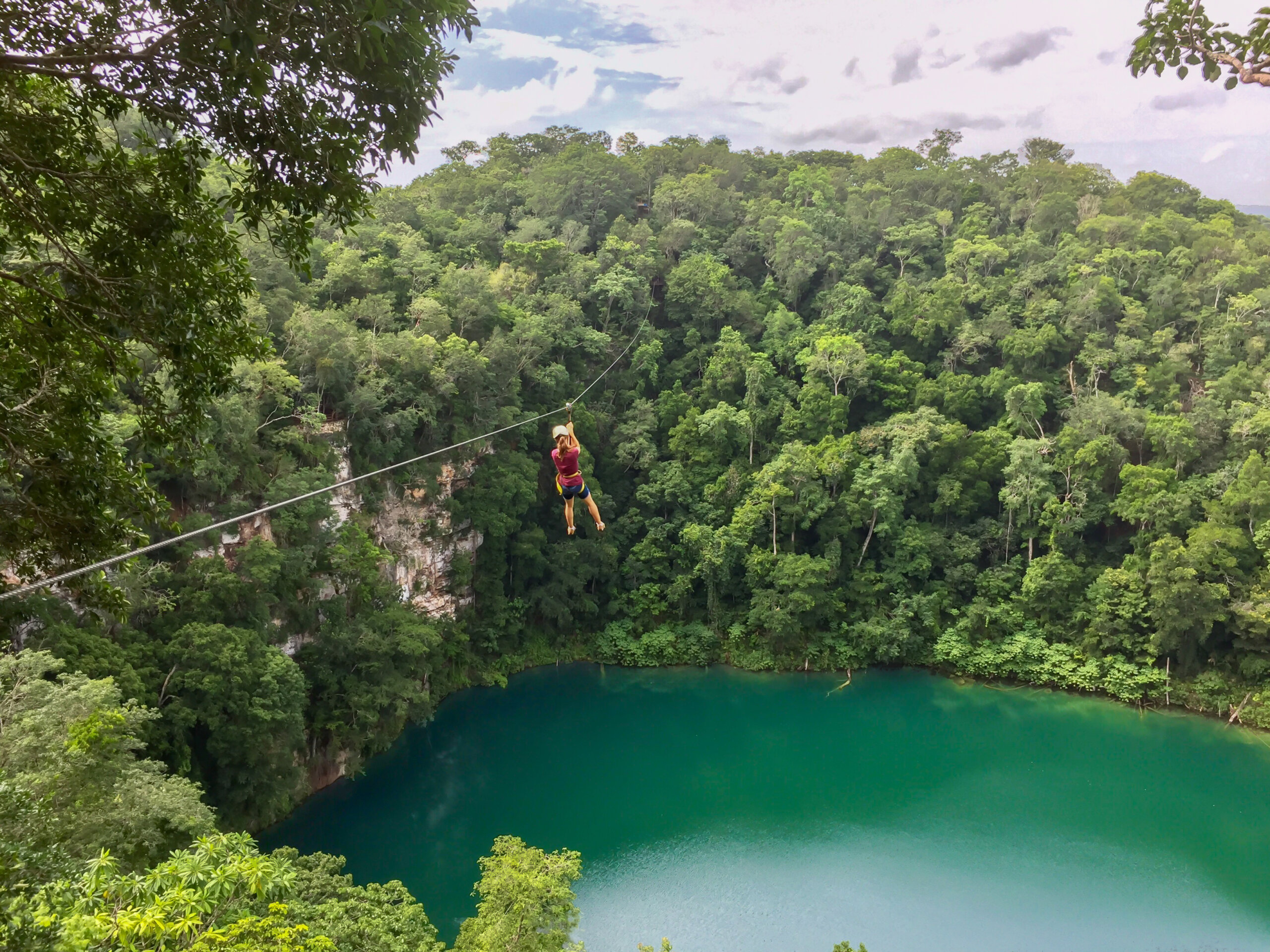 Girl ziplining over the water of a cenote in the Mexican jungle