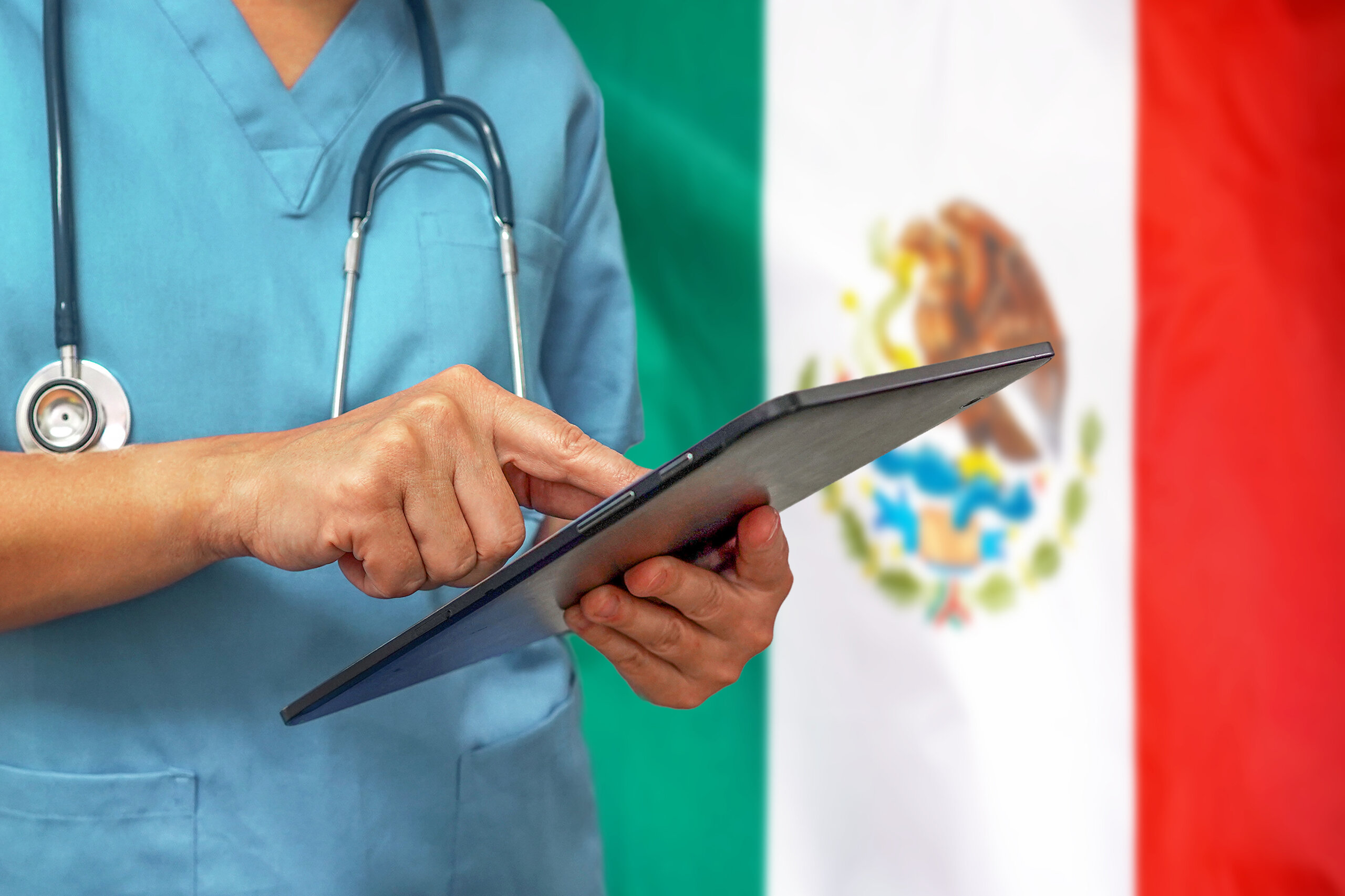 Surgeon or doctor using a digital tablet on the background of the Mexico flag. Medical equipment or medical network, technology and diagnostics in Mexico.