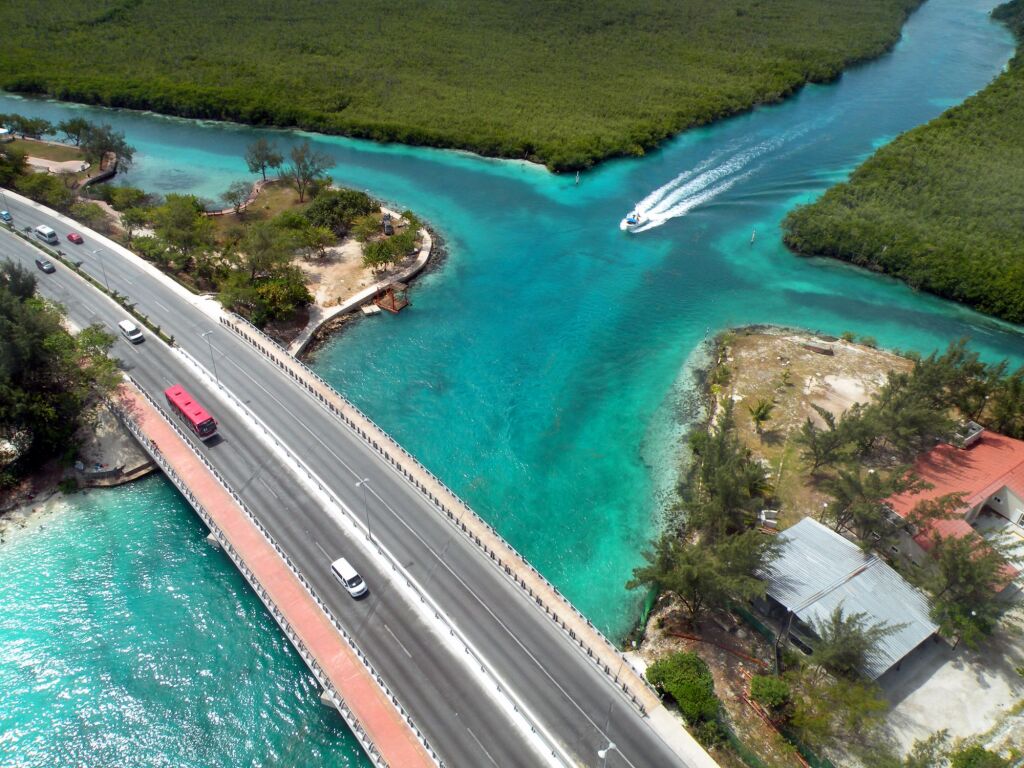 Aerial view of a cancun road over the sea with cars and a boat at full speed