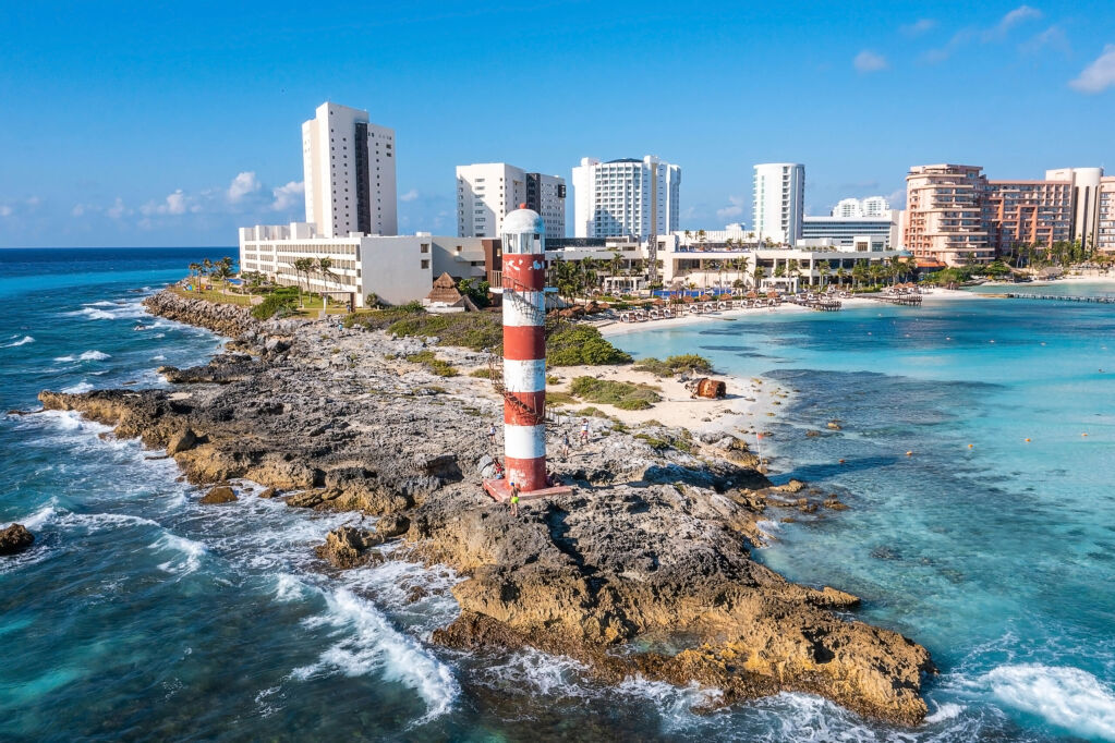 Aerial view of Punta Cancun Lighthouse. The Lighthouse adorned with white and red stripes and located in a rocky area.
