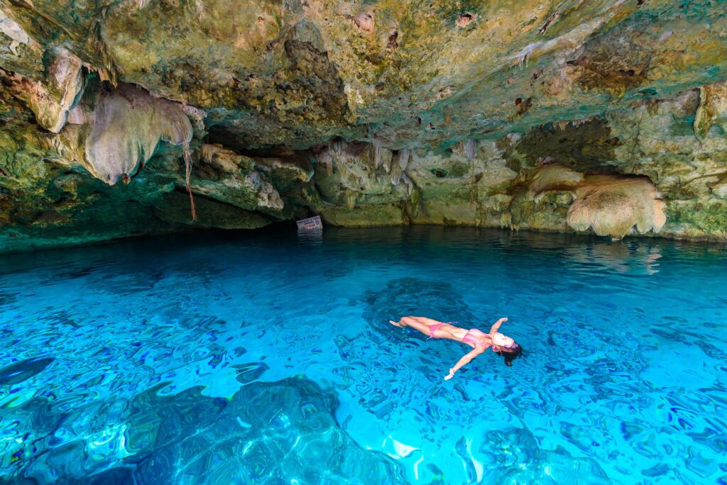 Cenote Dos Ojos w Quintana Roo w Meksyku. Ludzie pływają i nurkują w czystej, niebieskiej wodzie. Ten cenot znajduje się w pobliżu Tulum na półwyspie Jukatan, Meksyk.