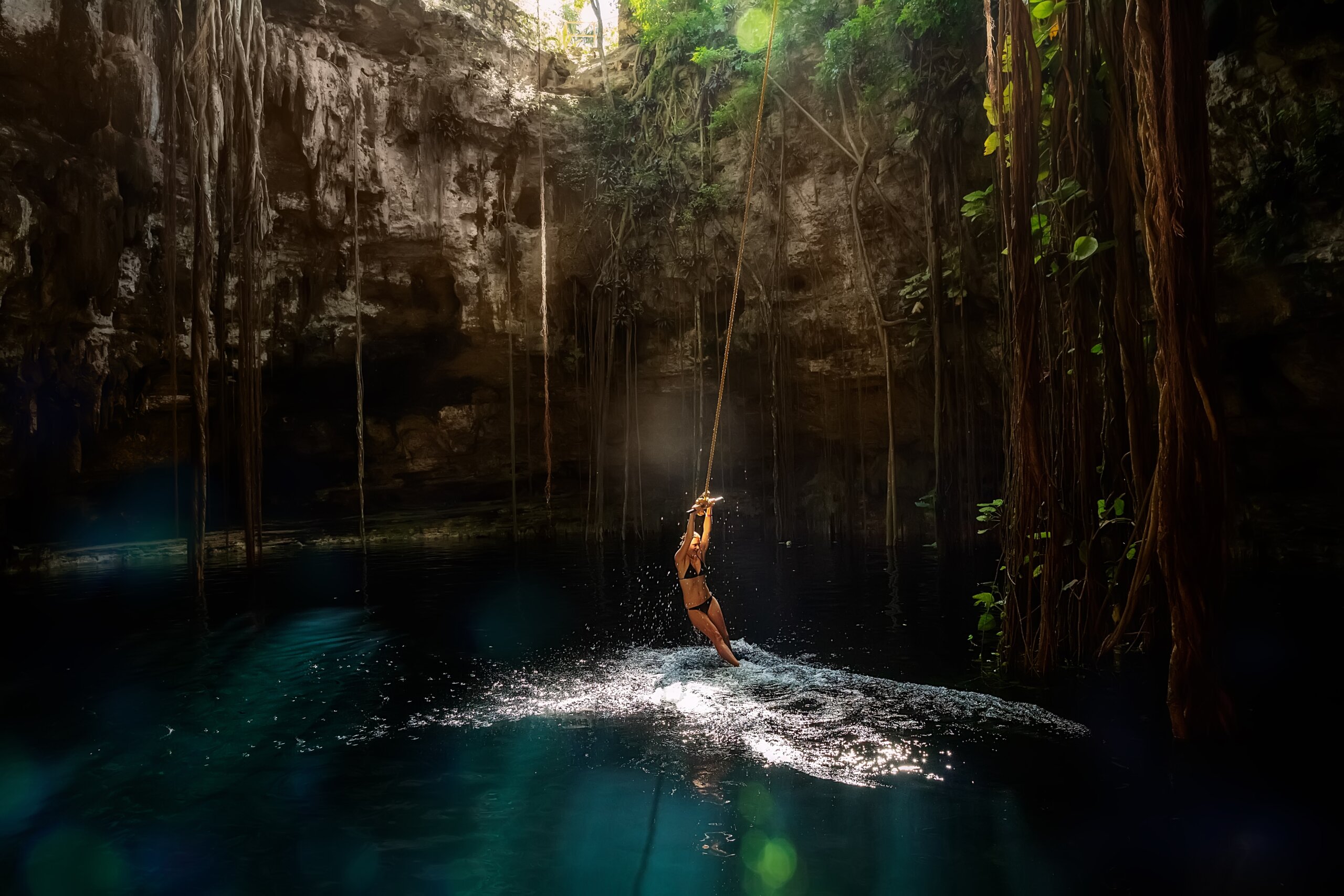 Cenote Ik-Kil Yucatan. Girl on a bungee. Mexico.