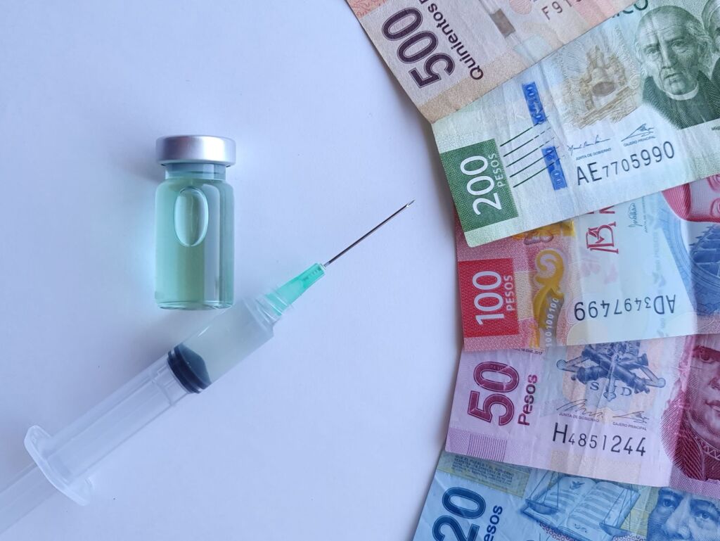 mexican banknotes, syringe and bottle with medicine
