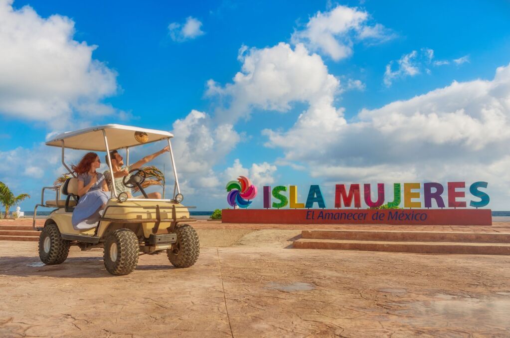Uśmiechnięta i szczęśliwa para jazdy wózek golfowy na tropikalnej plaży na Isla Mujeres, Meksyk