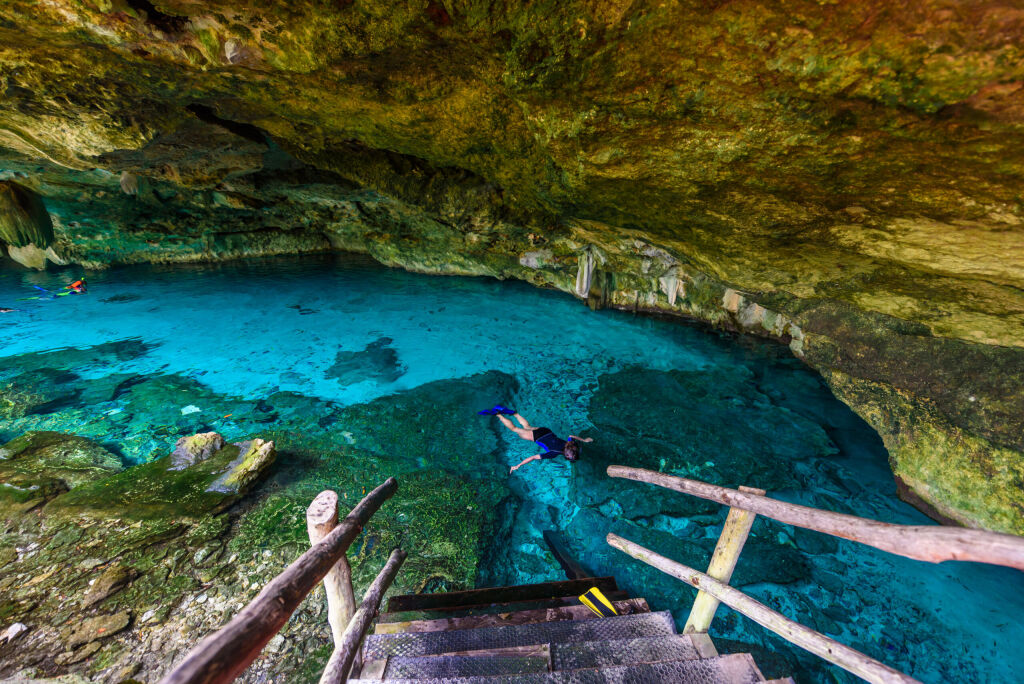 Cenote Dos Ojos in Quintana Roo, Mexico. People swimming and snorkeling in clear blue water. This cenote is located close to Tulum in Yucatan peninsula, Mexico.