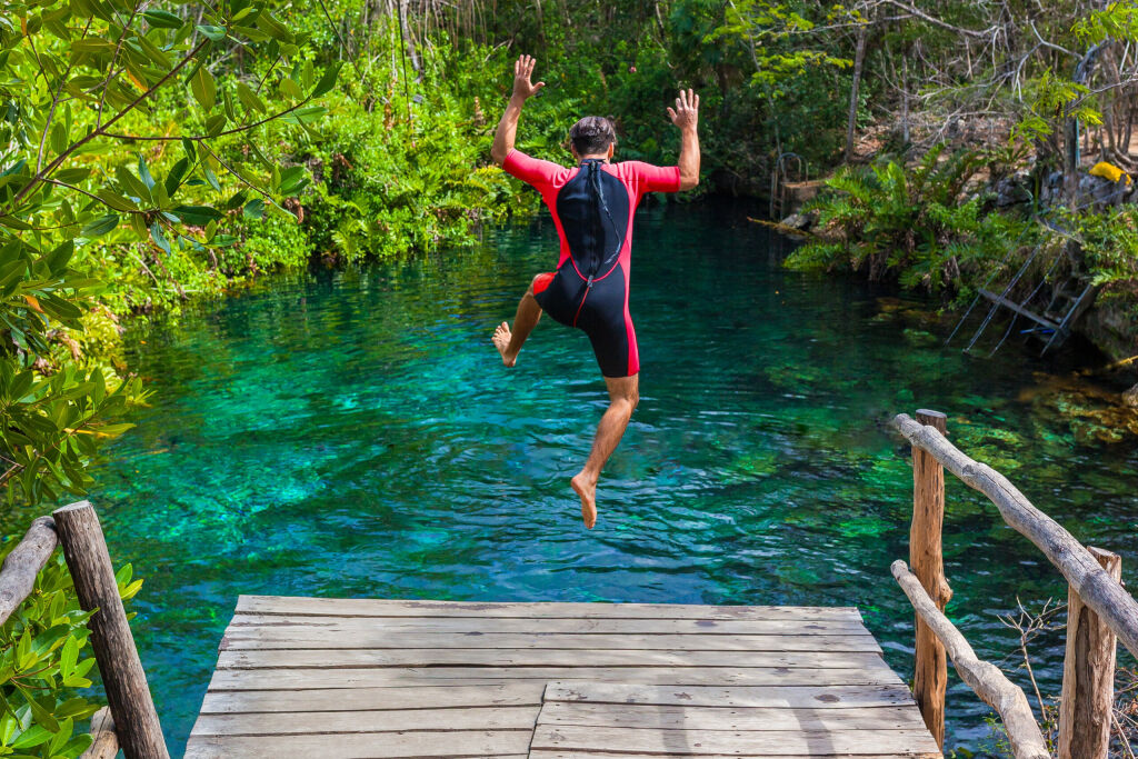 man jumping into a cenote in the Riviera Maya