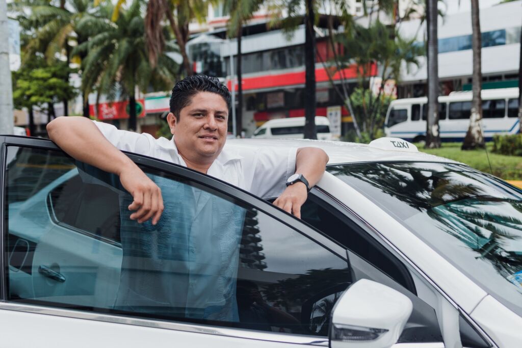 portrait of latin taxi driver man with car on background at city street in Mexico in Latin America, Hispanic people