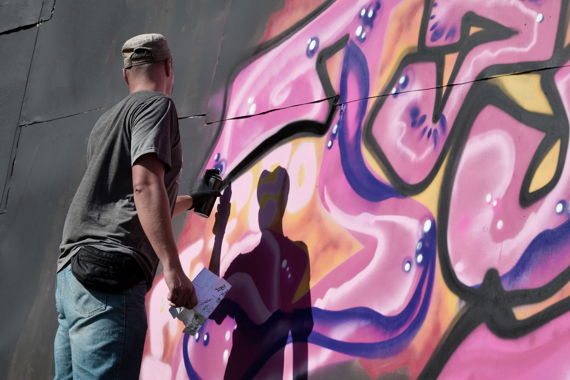 Młody mężczyzna malujący mural na ścianie. Podobne znajdziesz w Akumal.