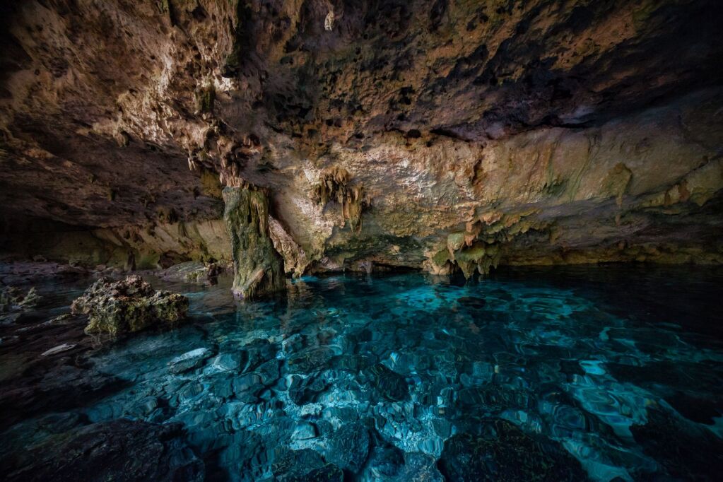 Akumal. Mexico. Cenote Dos Ojos. A stone wall hangs over clear blue water