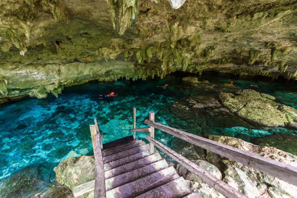 Cenote Dos Ojos in Quintana Roo, Mexico. People swimming and snorkeling in clear water. This cenote is located close to Tulum in Yucatan peninsula, Mexico.